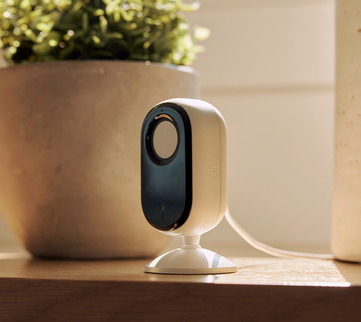 Arlo Essential Indoor camera on wooden table coffee table