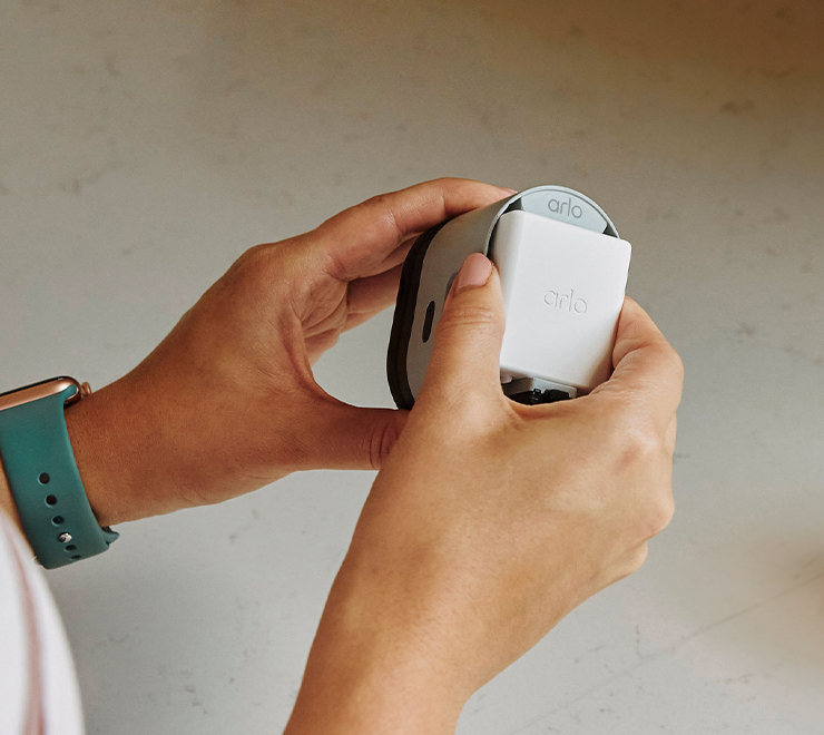 Person holding Arlo camera in the process of removing the battery